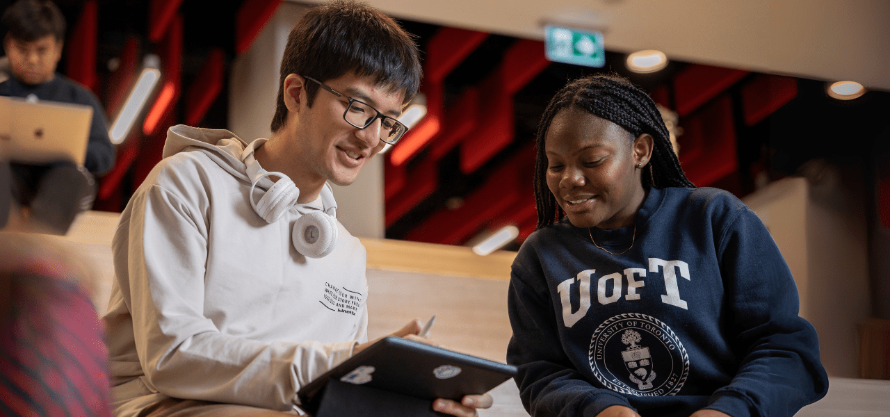 One student holding a tablet while another student looks at the screen.